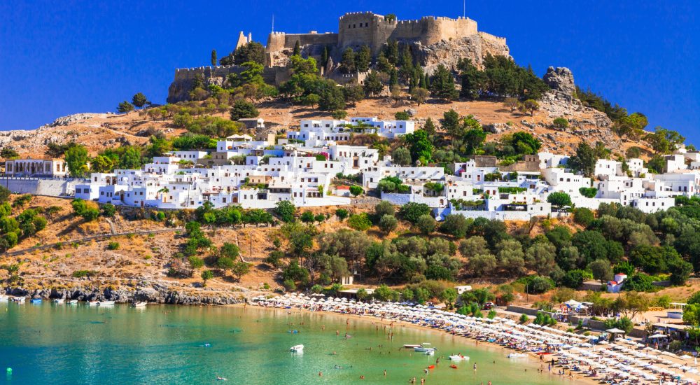 Acropolis of Lindos on Rhodes island, with white houses and a sandy beach below